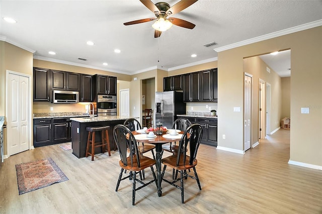 dining room with sink, ceiling fan, crown molding, and light wood-type flooring