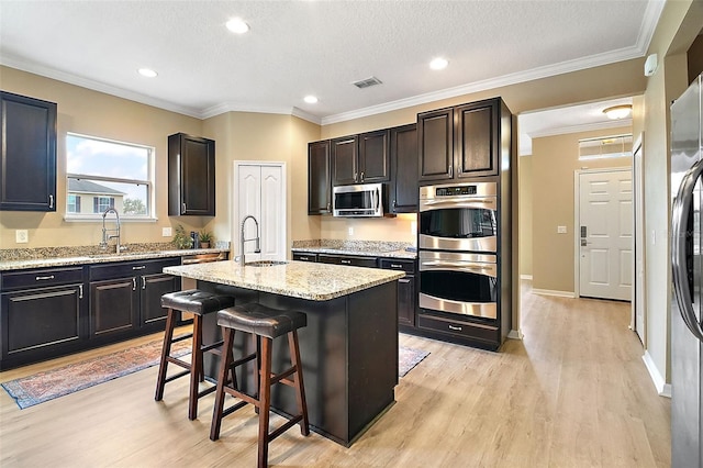 kitchen with an island with sink, appliances with stainless steel finishes, a kitchen breakfast bar, and sink