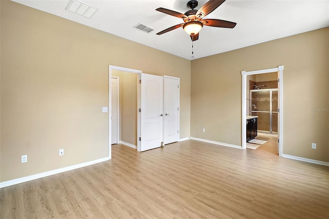 unfurnished bedroom featuring ceiling fan, light wood-type flooring, and ensuite bath