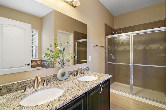 bathroom with hardwood / wood-style floors, a shower with shower door, and vanity