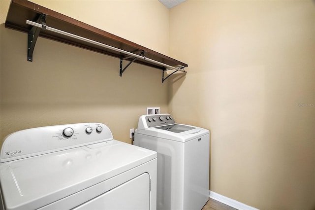 clothes washing area with wood-type flooring and independent washer and dryer