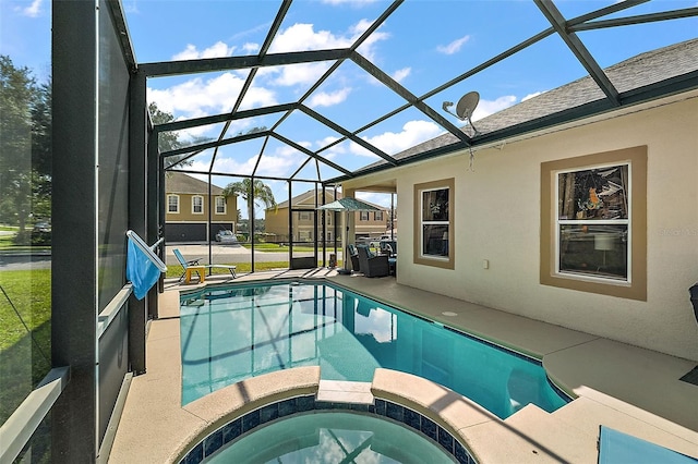 view of pool with an in ground hot tub, glass enclosure, and a patio