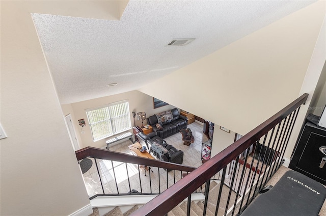 stairs featuring a textured ceiling and vaulted ceiling