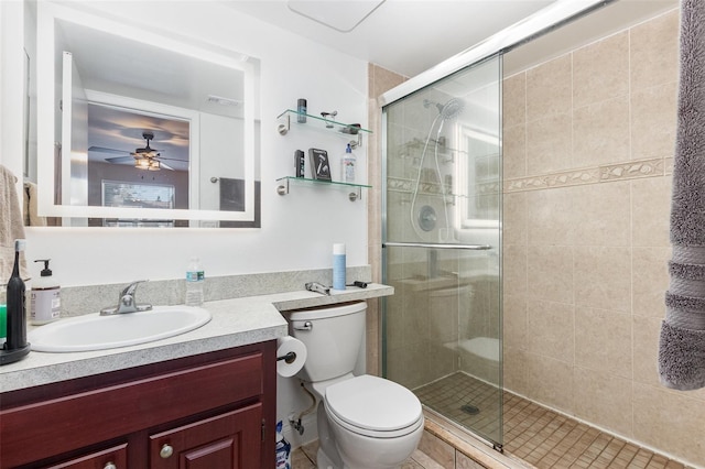 bathroom featuring vanity, toilet, ceiling fan, and a shower with door