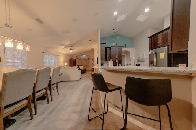 kitchen featuring vaulted ceiling, ceiling fan, light hardwood / wood-style flooring, stainless steel fridge with ice dispenser, and hanging light fixtures