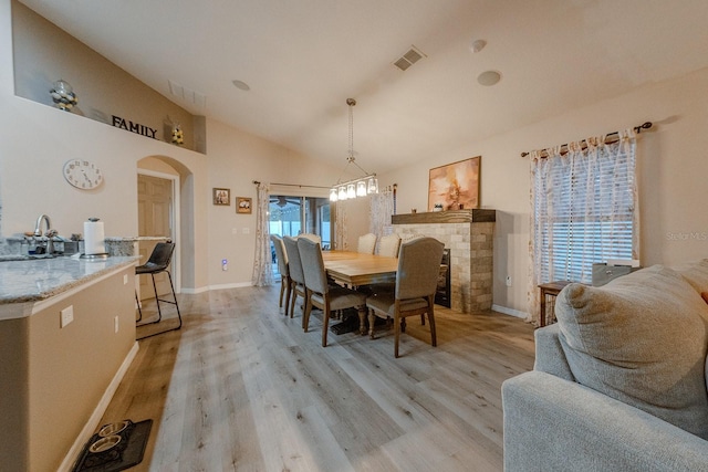 dining area with sink, light hardwood / wood-style flooring, and vaulted ceiling