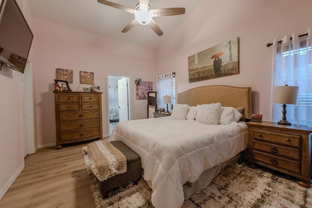 bedroom featuring ceiling fan, light wood-type flooring, ensuite bathroom, and high vaulted ceiling