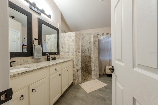 bathroom featuring vanity, vaulted ceiling, and tiled shower