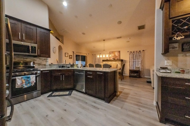 kitchen featuring kitchen peninsula, decorative backsplash, high vaulted ceiling, appliances with stainless steel finishes, and sink