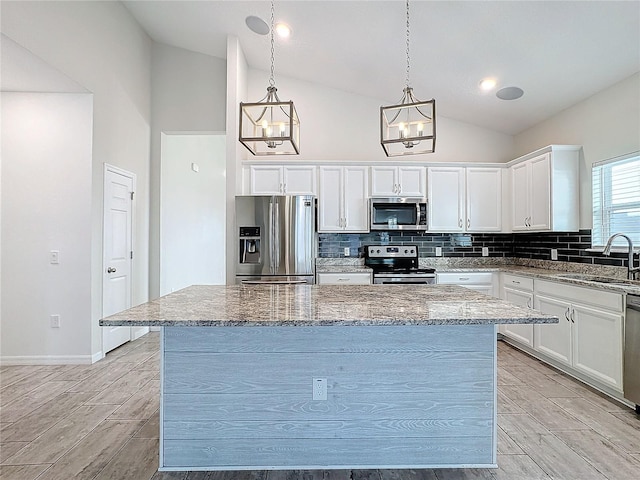 kitchen featuring white cabinetry, appliances with stainless steel finishes, sink, hanging light fixtures, and a center island