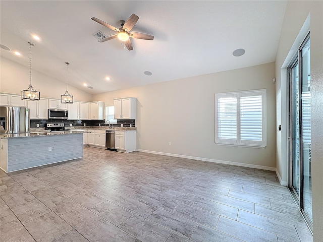 kitchen with white cabinetry, stainless steel appliances, lofted ceiling, light stone countertops, and pendant lighting