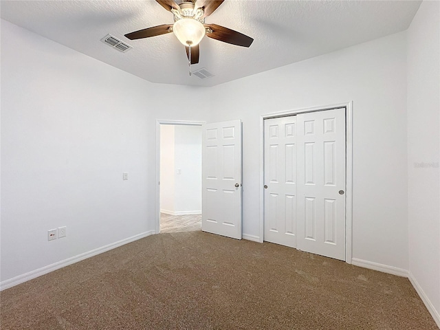 unfurnished bedroom with ceiling fan, a textured ceiling, a closet, and carpet floors