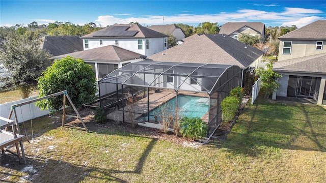 rear view of property with a lanai, a lawn, and a fenced in pool