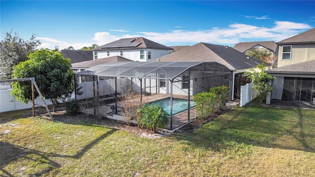 rear view of property featuring a fenced in pool, glass enclosure, and a yard