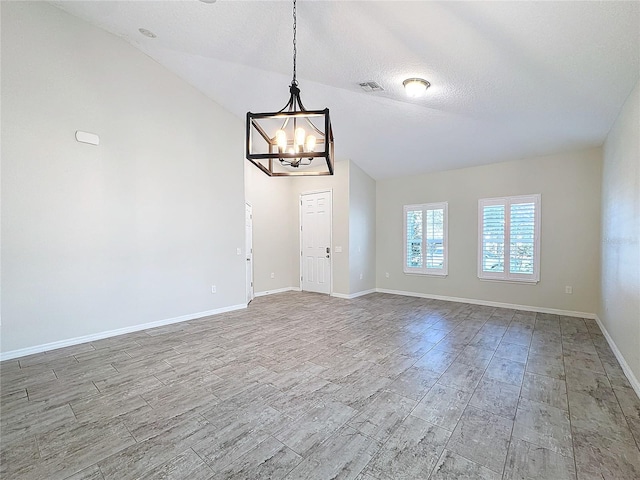 spare room with a textured ceiling, a chandelier, and vaulted ceiling