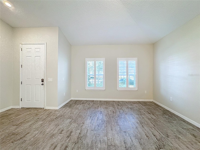 unfurnished room with light hardwood / wood-style floors and a textured ceiling