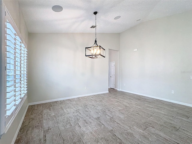 empty room featuring lofted ceiling, a notable chandelier, and a textured ceiling