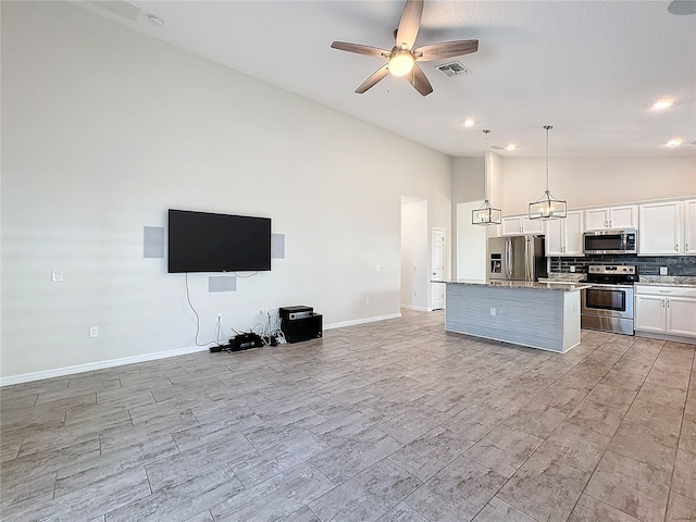 kitchen featuring ceiling fan with notable chandelier, white cabinets, a kitchen island, decorative light fixtures, and stainless steel appliances