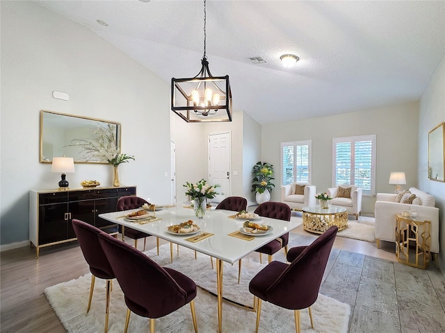 dining area with vaulted ceiling, a textured ceiling, a chandelier, and hardwood / wood-style flooring