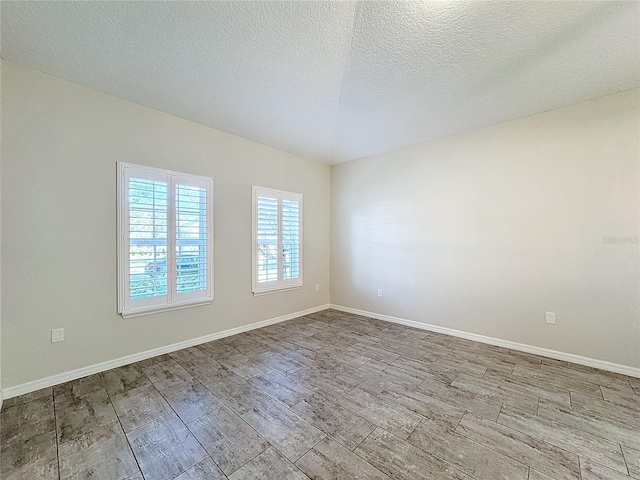 empty room with light wood-type flooring and a textured ceiling