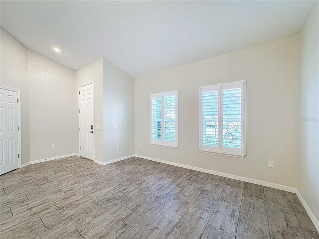 empty room featuring a textured ceiling and lofted ceiling