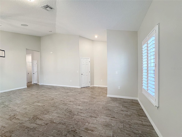 unfurnished room featuring a textured ceiling and lofted ceiling