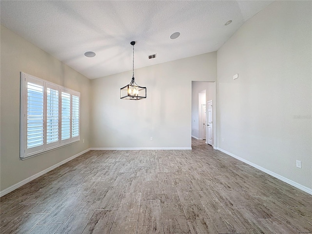 spare room featuring vaulted ceiling, a chandelier, and a textured ceiling