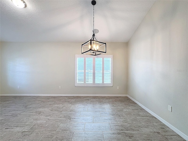 empty room with a textured ceiling and a notable chandelier