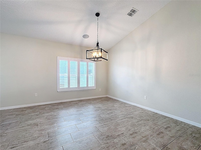 unfurnished room featuring a textured ceiling, lofted ceiling, and an inviting chandelier