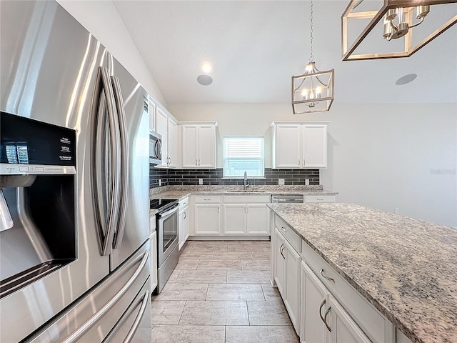 kitchen featuring an inviting chandelier, appliances with stainless steel finishes, backsplash, white cabinets, and light stone counters