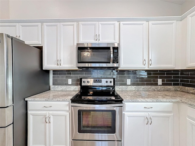 kitchen with tasteful backsplash, appliances with stainless steel finishes, white cabinetry, and light stone counters