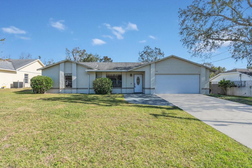 ranch-style home featuring cooling unit, a front lawn, and a garage