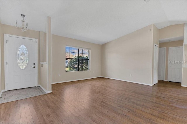 foyer entrance featuring a notable chandelier, vaulted ceiling, and hardwood / wood-style flooring