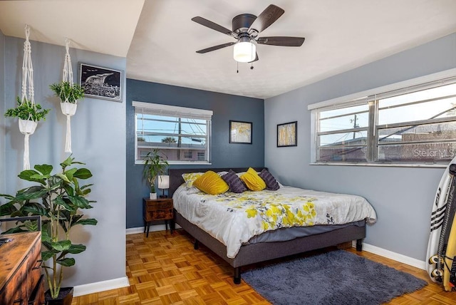 bedroom featuring ceiling fan, multiple windows, and light parquet floors