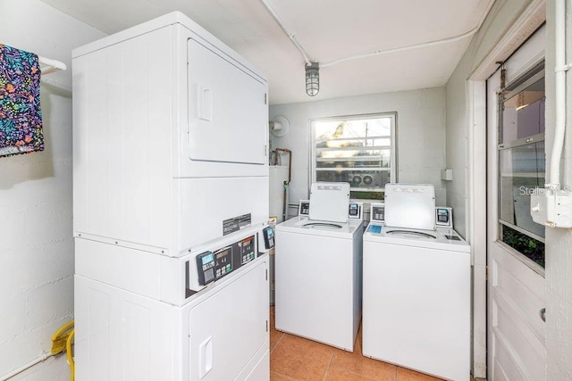 clothes washing area with washer and clothes dryer, light tile patterned floors, stacked washer / dryer, and water heater