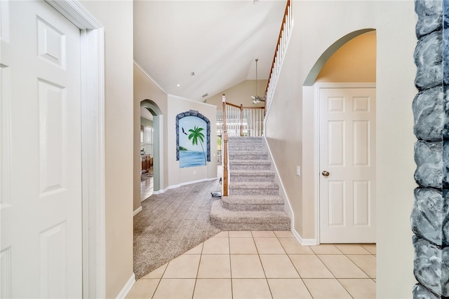 foyer entrance with ceiling fan, light tile patterned flooring, lofted ceiling, and crown molding