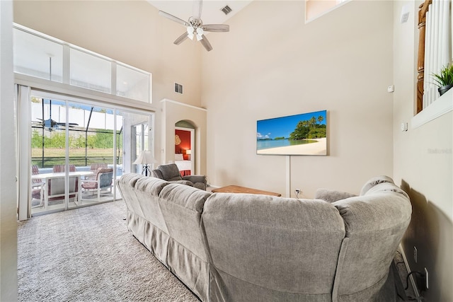 living room with carpet flooring, ceiling fan, and a high ceiling