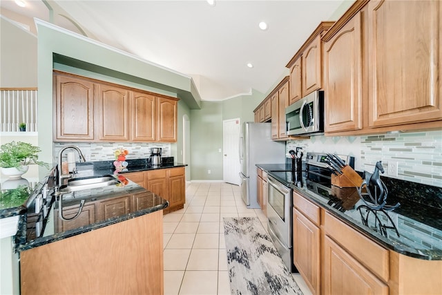 kitchen featuring sink, tasteful backsplash, dark stone counters, light tile patterned floors, and appliances with stainless steel finishes