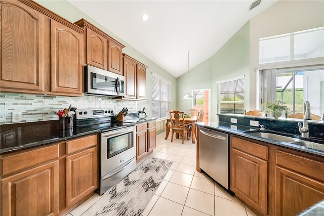 kitchen with dark stone countertops, sink, lofted ceiling, and appliances with stainless steel finishes