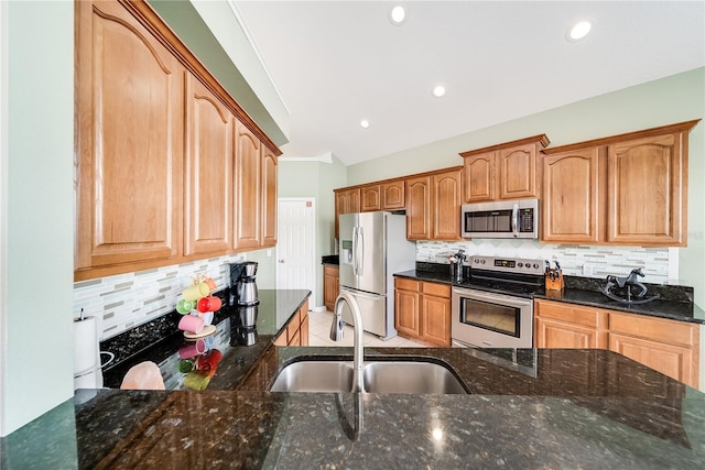 kitchen featuring decorative backsplash, dark stone countertops, sink, and appliances with stainless steel finishes