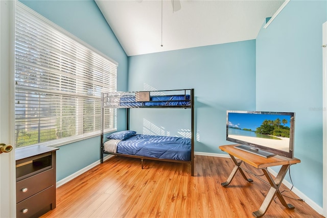 bedroom featuring multiple windows, ceiling fan, wood-type flooring, and lofted ceiling