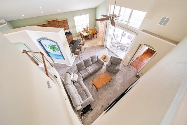 living room featuring ceiling fan, carpet floors, and a high ceiling