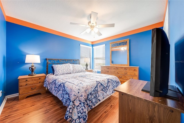 bedroom with wood-type flooring, a textured ceiling, and ceiling fan