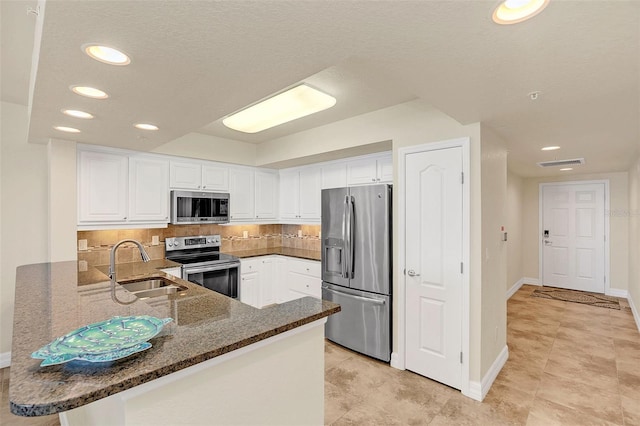 kitchen featuring white cabinets, kitchen peninsula, appliances with stainless steel finishes, and sink