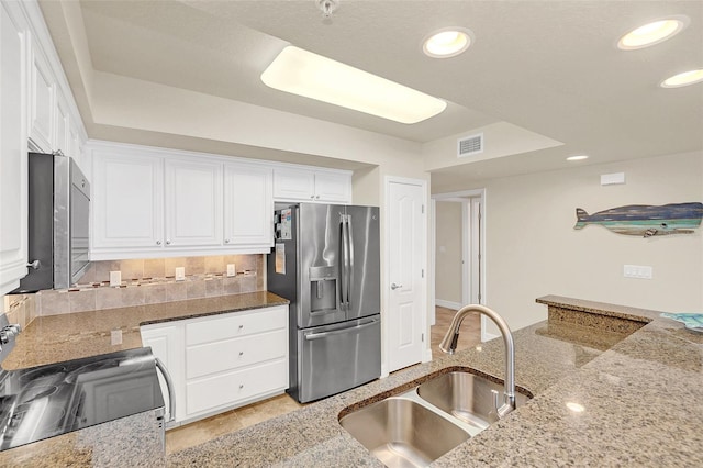 kitchen featuring light stone countertops, appliances with stainless steel finishes, white cabinetry, tasteful backsplash, and sink