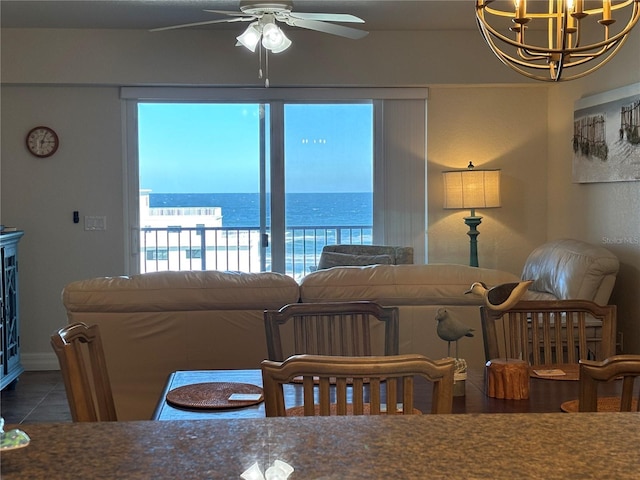 tiled dining space featuring ceiling fan with notable chandelier and a water view