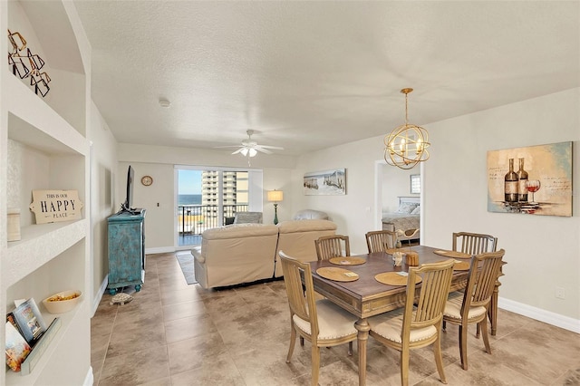 dining room with ceiling fan with notable chandelier and a textured ceiling