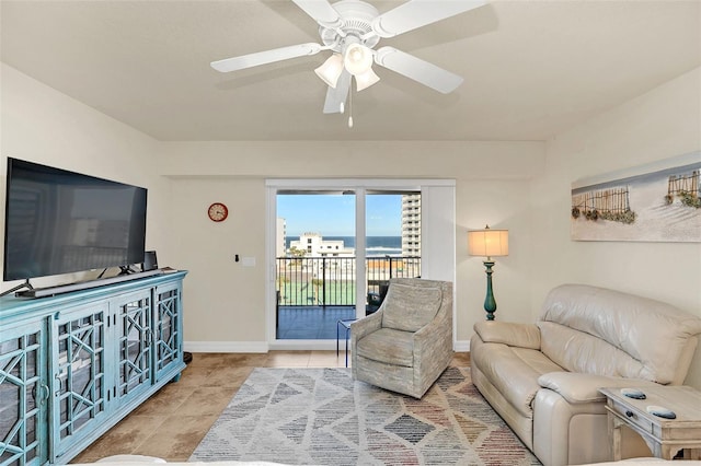 tiled living room featuring ceiling fan and a water view