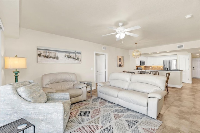 living room featuring ceiling fan with notable chandelier