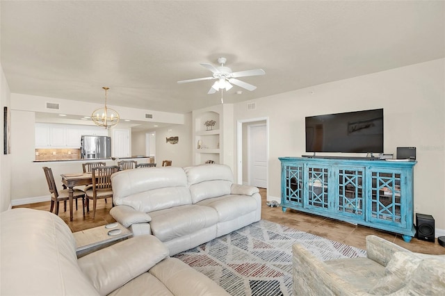 living room with ceiling fan with notable chandelier and built in features